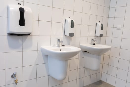 This is a clean and modern bathroom that showcases twin sinks and hand dryers for the convenience of the public