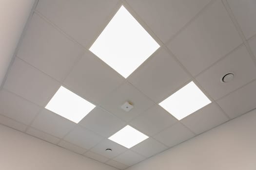 A bright and modern office ceiling design that prominently features advanced LED panel lighting for efficiency