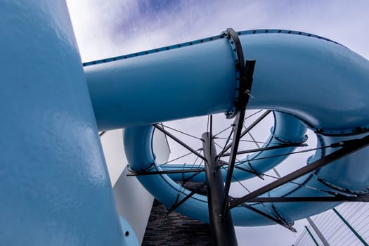 An exciting and vibrant blue water slide elegantly twisting through the bright sky at a popular amusement water park