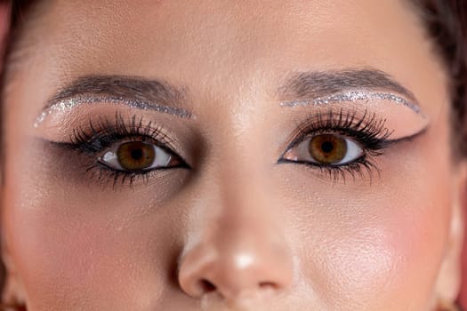 An artistic closeup shot that brilliantly showcases stunning eye makeup embellished with glitter and dramatic lashes