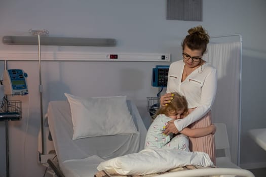 A caring mother embraces her child in a hospital room, symbolizing love and support during tough times.