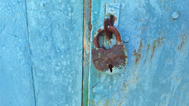Rusty lock on weathered blue door: urban decay and vintage charm.