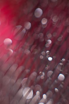 glare from water on a black mesh on a blurred red background. Abstract background.Close up. Defocused