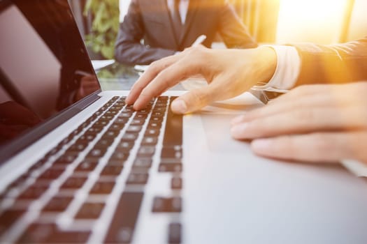 Closeup view of businessman working at sunny office on modern laptop