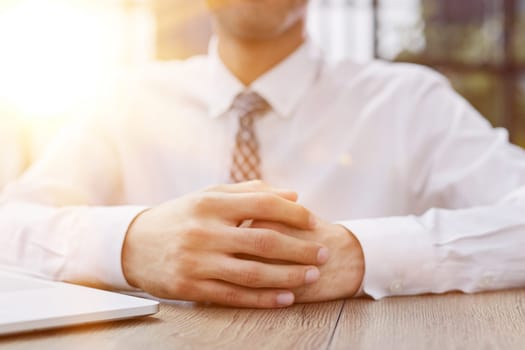 Businessman folded his hands at the table in a modern office.