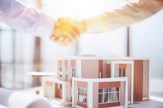 handshake against the background of a model of a house under construction