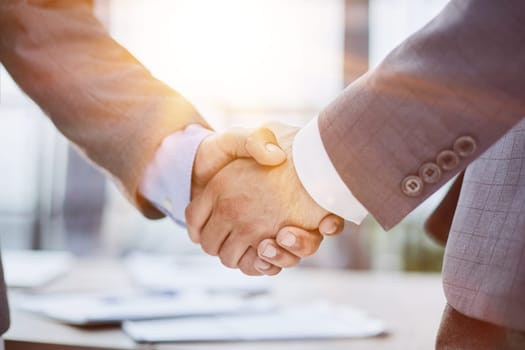 handshake in the office of two businessmen at the desk