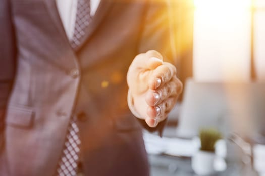 Businessman manager stretching out hand for handshake to partner in office closeup.