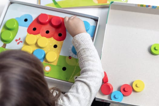 Two year old girl playing puzzle board game. High quality photo