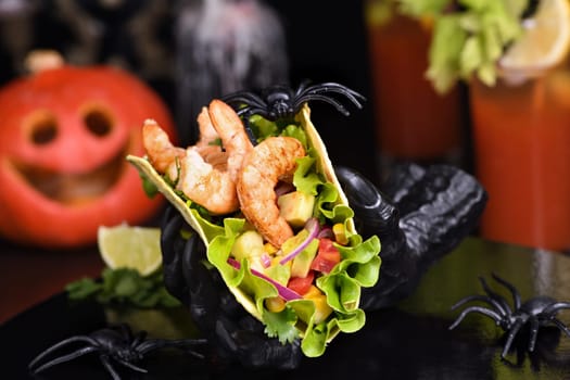 Black monster hand holding tacos crispy fried shrimp. Halloween party serving