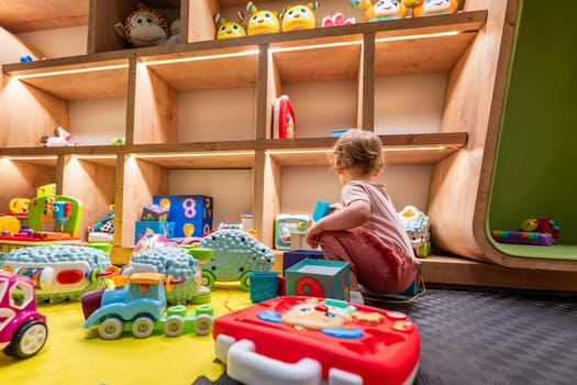 Toddler playing with colorful toys and building blocks in a bright and organized playroom