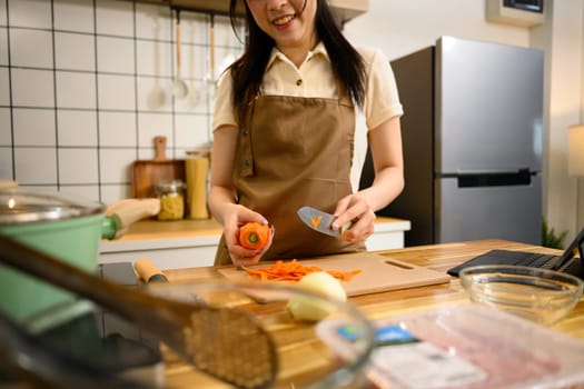 Smiling woman in an apron preparing ingredients for spaghetti in a cozy kitchen.