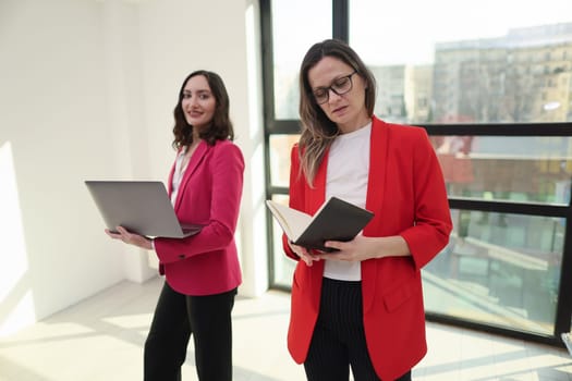 Confident businesswoman holding a clipboard while standing in an office.