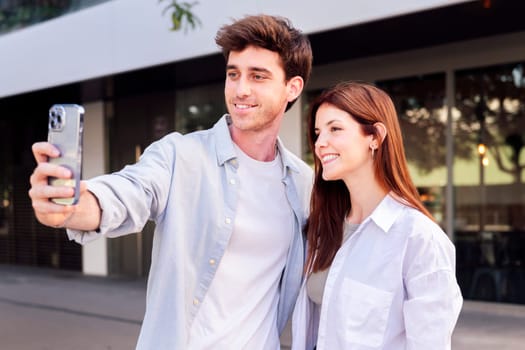 man and a woman are taking a selfie together, the man is holding a cell phone and the woman is smiling, concept of technology and urban lifestyle