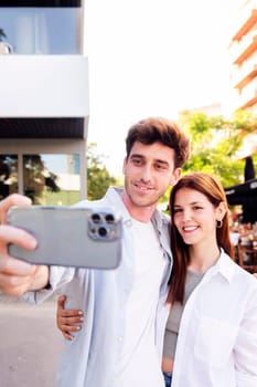 man and woman smiling happy taking a selfie together, the man is holding a cell phone and the woman is smiling, scene is happy and lighthearted