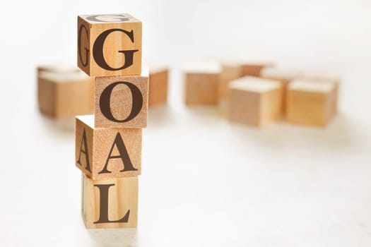 Four wooden cubes arranged in stack with word GOAL on them, space for text / image at down right corner