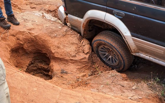 4wd vehicle driving over road with extreme holes and bumps, close up on rear wheel - roads are in very bad conditions in Andringitra, Madagascar, especially after rain
