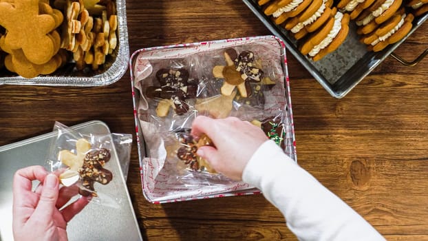 Flat lay. Lovingly homemade gingerbread and sugar cookies, half-dipped in rich chocolate, nestled in decorative Christmas tin boxes perfect for seasonal gifting.