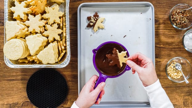 Flat lay. Creating snowflake-shaped cutout sugar cookies, dipped in chocolate, and adorned with different toppings.