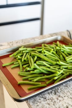 Watch as fresh green beans are beautifully roasted to perfection on a baking sheet with a silicone mat, adding a burst of flavor to your meal.
