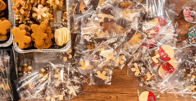 Carefully packaging Christmas cutout cookies, half-dipped in chocolate, sprinkled with crushed nuts, and presented in clear cellophane wrapping.