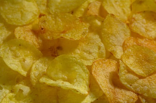 Golden-brown potato chips lay scattered, inviting snack lovers to enjoy their crispy texture and savory flavor.