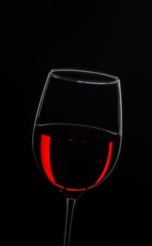 A sophisticated glass showcases deep red wine, reflecting light beautifully in contrast with a black backdrop.