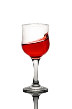 A refreshing drink glistens in sunlight, casting shadows while the rich red liquid swirls artfully around the glass.