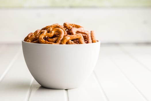 Heart shaped pretzel in bowl  on a white table.