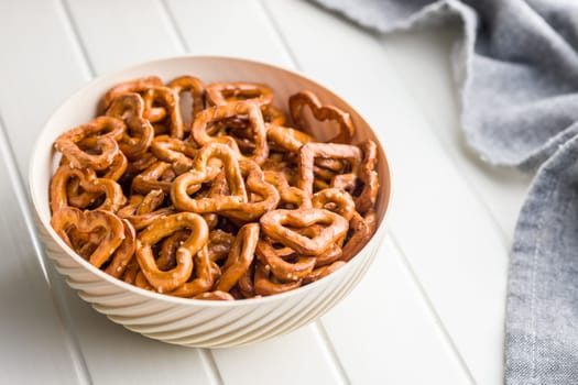 Heart shaped pretzel in bowl  on a white table.