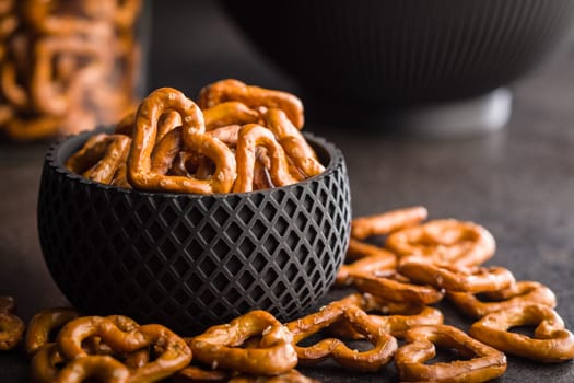 Heart shaped pretzel in bowl on a black table.