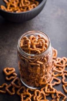 Heart shaped pretzel in jar on a black table.
