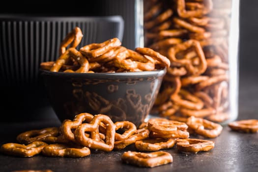 Heart shaped pretzel in bowl on a black table.