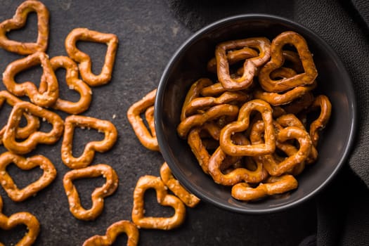 Heart shaped pretzel in bowl on a black table. Top view.