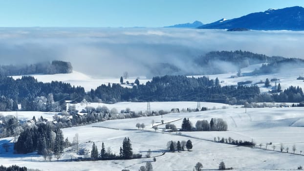 Drohnenaufnahme von Nebel im Tal vor den Allgäuer Alpen im Winter