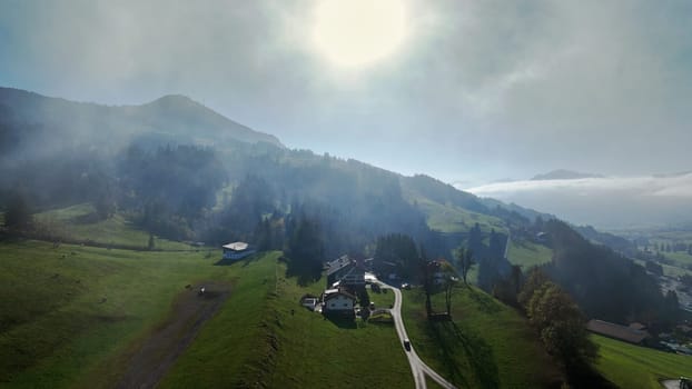Drohnenfoto von einer Berglandschaft mit Straße mit Nebel im Gegenlicht der Sonne