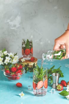 Bartender preparing a refreshing summer drink, mixing strawberries, mint, and ice in a glass for a delicious, thirst quenching experience