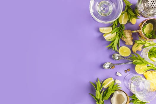 Fresh mint, lime, ginger, coconut, and pineapple arranged against a purple background with cocktail shaker and glasses for a vibrant summer drink