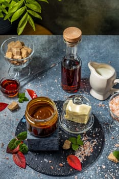 Preparing salted caramel sauce with butter, cream, brown sugar, fleur de sel and maple syrup on dark gray kitchen table
