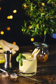 Vibrant pear and basil cocktail, infused with lemongrass, sits on a rustic wooden table, creating a refreshing and inviting scene