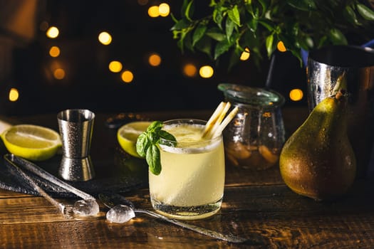 Tantalizing cocktail featuring pear and lemongrass, garnished with fresh basil, served in a rocks glass on a rustic wooden table