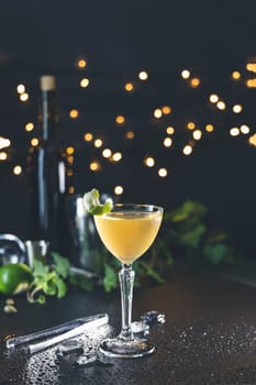 Refreshing cocktail served in elegant glass, garnished with lime and mint, sits on wet countertop against bokeh background