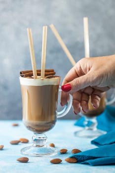 Barista preparing a delicious coffee with almond syrup, whipped cream, cinnamon sticks and eco friendly straws