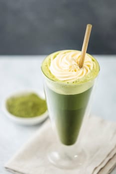 Refreshing iced matcha latte topped with whipped cream and served with an eco friendly straw, promoting a healthy and sustainable lifestyle