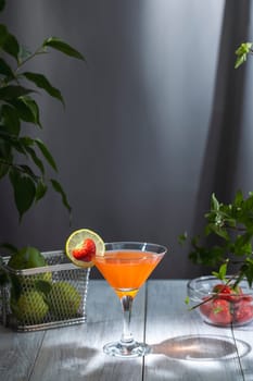 Vibrant orange cocktail is garnished with a fresh strawberry and lime slice, creating a refreshing summer drink