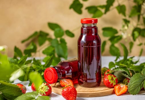 Two bottles of refreshing strawberry juice sit on a wooden board, surrounded by fresh strawberries and mint leaves, creating a vibrant and healthy scene