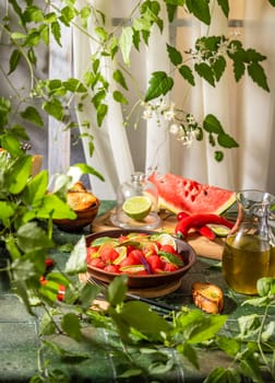 Bowl of watermelon salad with lime, herbs, chili pepper, olive oil, and toasted bread, creating a vibrant and refreshing summer dish