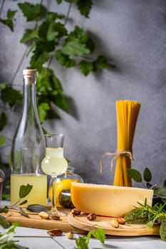 Bottle of limoncello, a glass, a wedge of cheese, and pasta create an enticing italian culinary scene