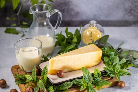 Parmesan cheese with milk, mint, macadamia nuts, and lemon on a wooden board, creating a fresh and flavorful culinary scene