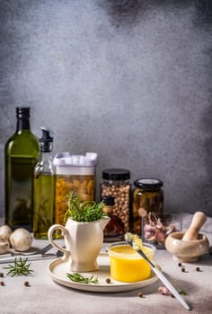 Ghee butter, rosemary, olive oil, pasta, chickpeas, spices, and other food ingredients arranged on kitchen table, creating a cozy cooking atmosphere
